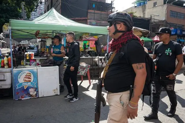 Pemandangan pasar lokal sebagai anggota kelompok sosial bersenjata berpatroli di area tersebut sambil memantau aktivitas komersial di Caracas, Venezuela, Minggu (4/1). Patroli berlangsung di tengah upaya pemerintah yang sedang berlangsung untuk mengatur harga dan menegakkan nilai tukar resmi yang ditetapkan oleh Bank Sentral Venezuela. 