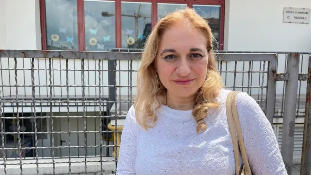A diretora Luana Scarfi, uma mulher de blusa branca e cabelos loiros
