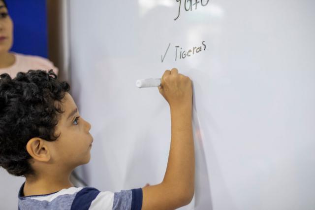 Un niño escribe en una pizarra una palabra con falta de ortografía