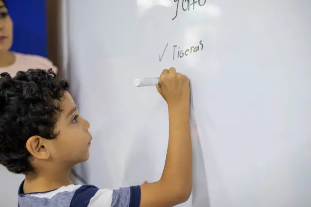 Un niño escribe en una pizarra una palabra con falta de ortografía