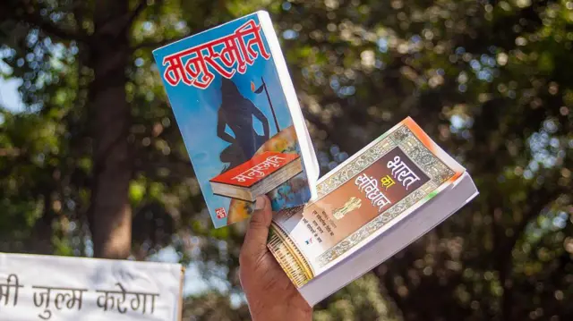 ২০২৫ সালে দিল্লিতে একটি বিক্ষোভে মনুস্মৃতি ও ভারতের সংবিধান হাতে এক বিক্ষোভকারী