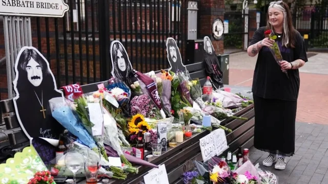 Женщина с букетом у лавки, заваленной цветами и портретами Осборна