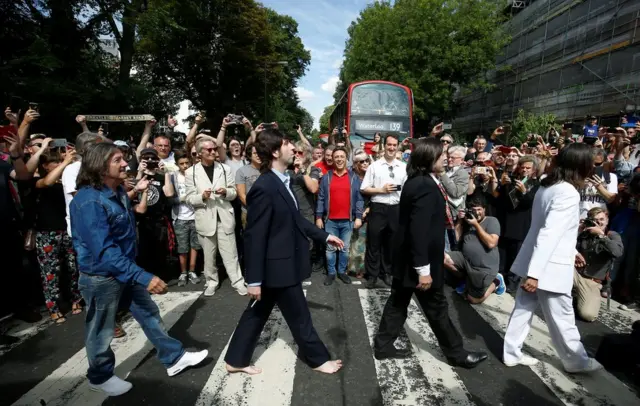 People gather round a pedestrian crossing in London