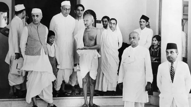 জওহরলাল নেহরু (বাঁয়ে) ও বল্লভভাই প্যাটেল (ডানদিকে দ্বিতীয়) - এর সঙ্গে মোহনদাস করমচাঁদ গান্ধী (মাঝে খালি গায়ে, কাঁদে চাদর নিয়ে) - ফাইল ছবি
