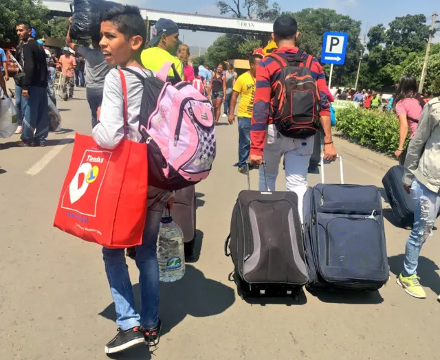 Personas cruzando la frontera con sus maletas