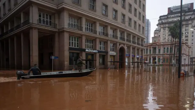 Imagem mostra dois homens usando barco para percorrer ruasceara e são paulo palpitesPorto Alegre