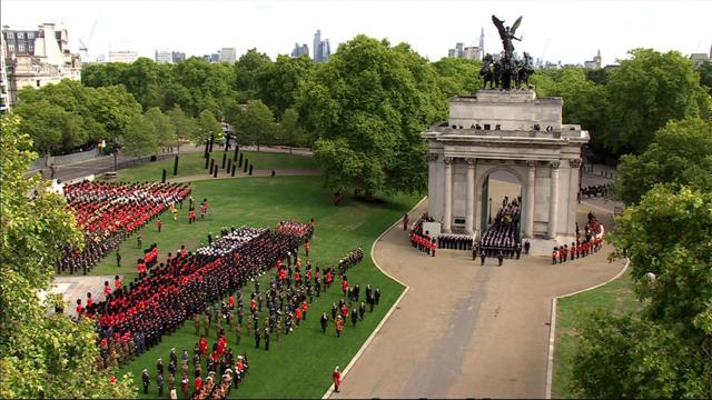 Um parque cheio de árvores no centro de Londres abriga um arco romano e é possível ver dezenas de soldados carregando um caixão através dele