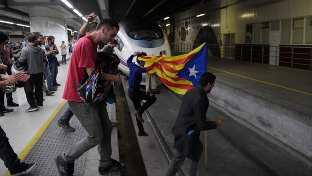 Protesters carrying a pro-independence Catalan Estelada flag jump on tracks to block trains at the Sants Station in Barcelona during a strike called by a pro-independence union in Catalonia on November 8, 2017.