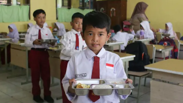 Siswa menerima porsi makan siang pada hari pertama program makan gratis di SD Negeri Kedung Badag 1 Bogor, Jawa Barat, pada 6 Januari 2025.