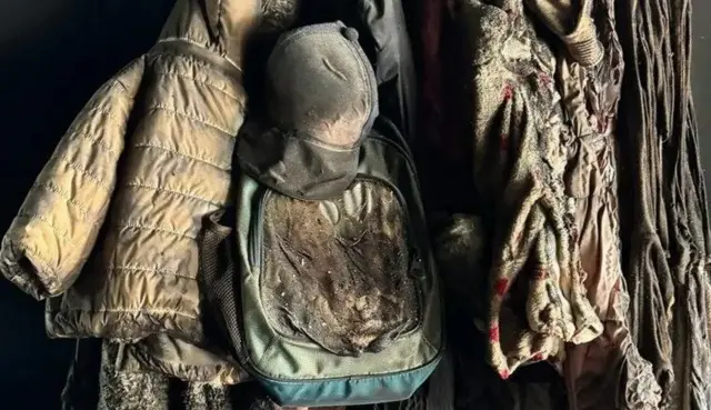 Des vêtements et le sac à dos d'un enfant sont encore suspendus dans une maison incendiée dans le kibboutz.