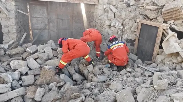 地震灾区有很多房屋被毁、建筑物倒塌。救援人员在废墟中搜寻生还者,并为当地居民分发厚毛毯。