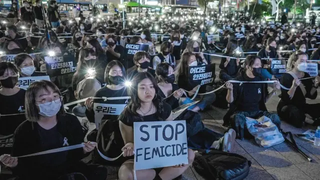 在2022年首尔的一场抗议活动中,一名女子高举写着“停止女性杀害(stop femicide)”的标语。