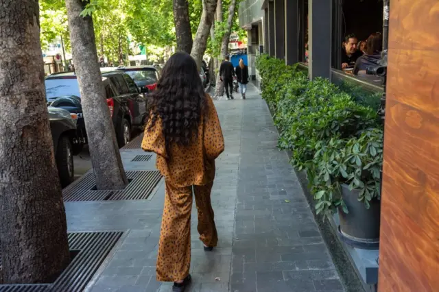 دختری بدون حجاب در خیابانی در تهران راه می‌رود