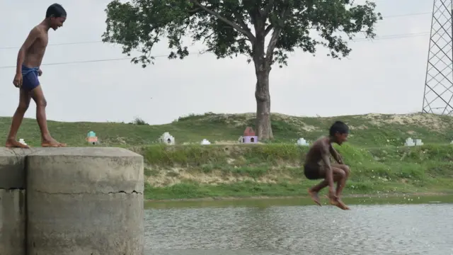 गांव के तालाब में तैरते बच्चे