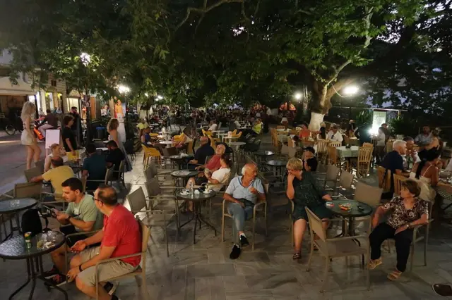 Lokalni mieszkańcy i turyści siedzą wieczorem przy stolikach na greckiej wyspie Lefkada 