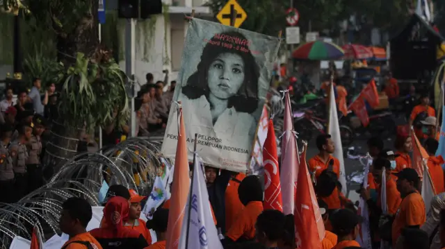 Simpatisan dari Partai Buruh membentangkan poster wajah Marsinah saat berunjuk rasa di depan Kantor Gubernur Jawa Timur di Surabaya, Jawa Timur, Senin (1/5/2023).