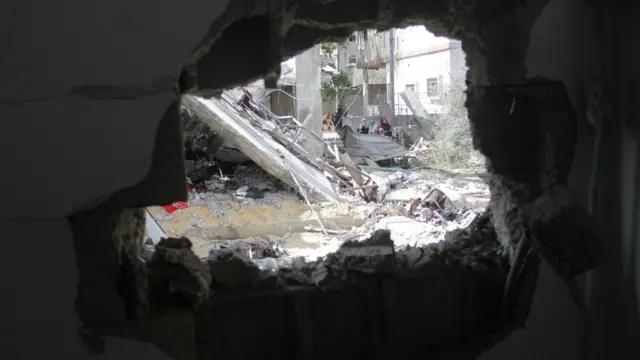 فلسطينيون يسيرون بجانب موقع تعرض تعرض لغارة إسرائيلية في بيت لاهيا شمال قطاع غزة