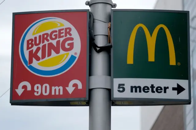 Una señal de tránsito en la que se ven los logos de Burger King y de McDonald's 
