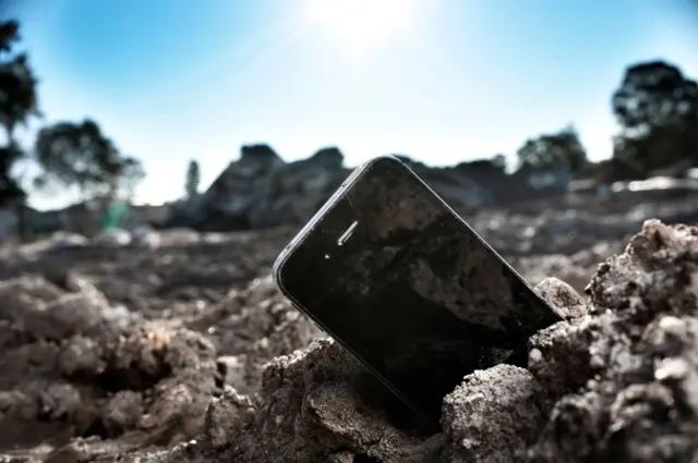 Sebuah ponsel di atas tanah lunak.
