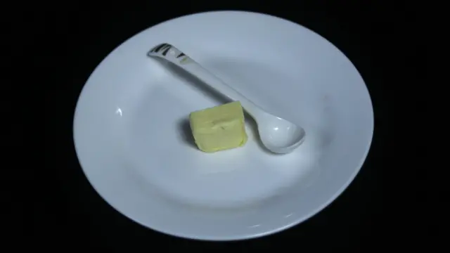 صورة تظهر قطعة صغيرة من الزبدة داخل طبق أبيض اللون.