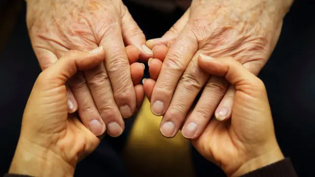 Manos jóvenes agarrando manos mayores