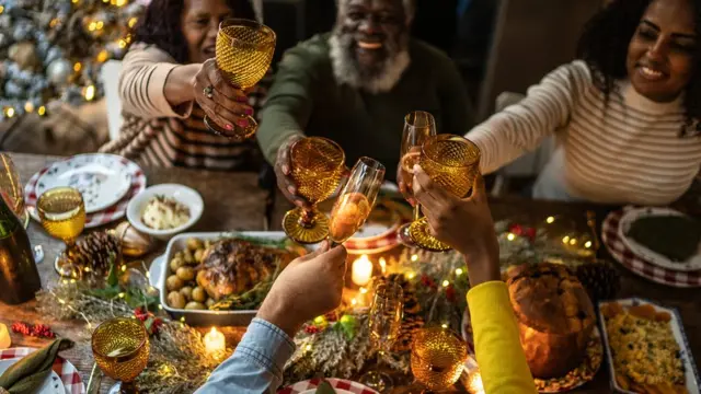 família brinda em torno da mesa com ceia de Natal