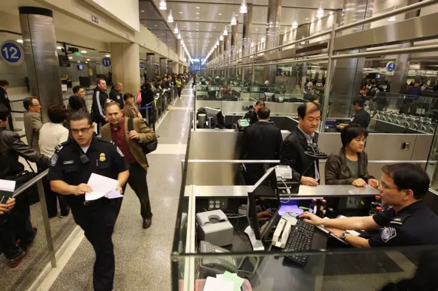 Agentes del CBP y viajeros en una aduana aeroportuaria de EE.UU.