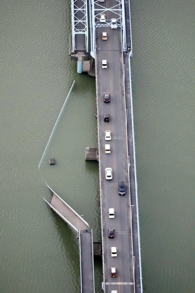 Un puente peatonal derribado. A su derecha se aprecia el tráfico de autos en el puente para vehículos que va en paralelo.