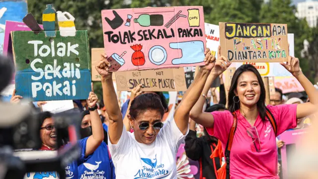 Mantan Menteri Kelautan dan Perikanan Susi Pudjiastuti (kiri) membawa poster saat mengikuti pawai bebas plastik di kawasan Sudirman, Jakarta, Minggu (30/07).