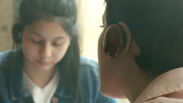 Dos personas con auriculares de traducción de la empresa Waverly Labs