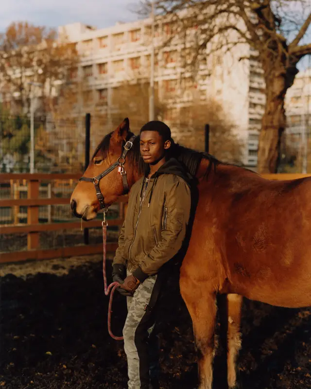 A teenager poses for a portrait with a horse