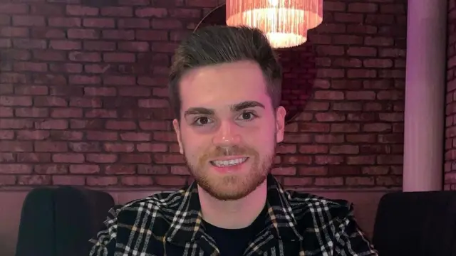 Um jovem sorridente com uma camisa xadrez