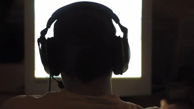 Человек в наушниках перед компьютером