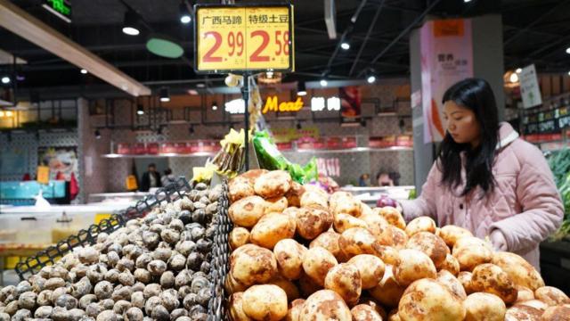 یک مشتری زن در ۹ مارس ۲۰۲۴ در سوپرمارکتی در شهرستان کونگجیانگ، استان کیاندونگنان میائو و استان خودمختار دونگ، در استان گوئیژو، سیب زمینی خریداری می کند