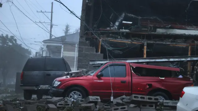 Vehicles damaged by collapsed building in New Orleans as Hurricane Ida makes landfall.