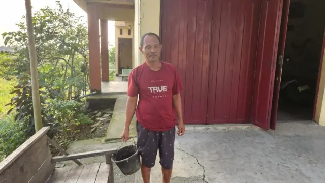 Seorang pria sedang menenteng ember.