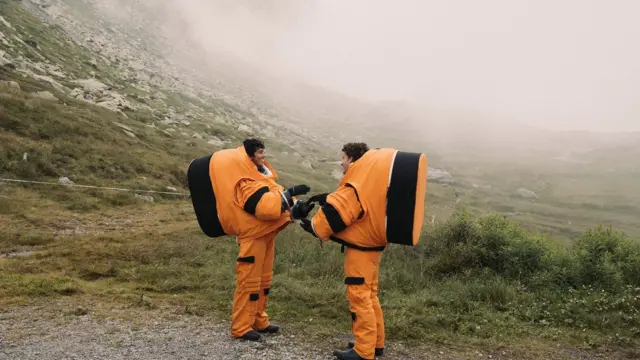 Duas pessoas com trajes laranja de astronauta nos Alpes suíços