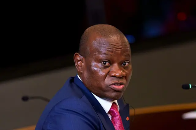 Le président gabonais, Brice Clotaire Oligui Nguema en costume bleu avec une cravate rouge bordeau, il tourne la tête et regarde dans la caméra.