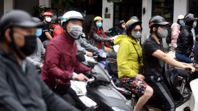 Luz verde para la vuelta a la normalidad: ciudadanos de Hanoi esperan en sus motonetas el cambio de luz.