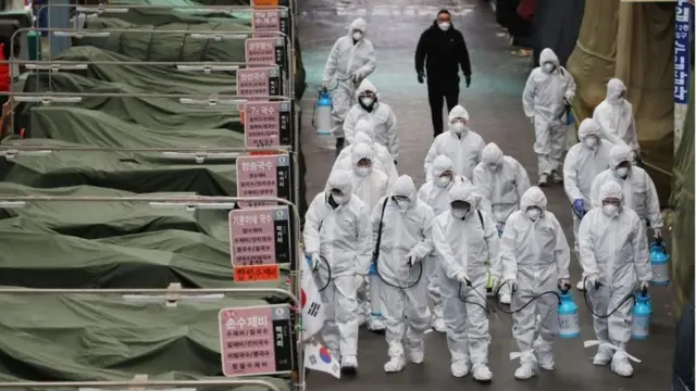 Market workers wearing protective gear spray disinfectant at a market in the southeastern city of Daegu on February 23, 2020