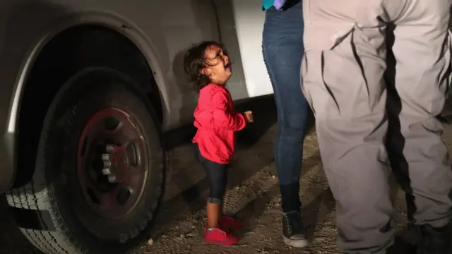 طفلة من هندوراس تبكي بينما يتم تفتيش أمها قبل فصلهما في معسكرين مختلفين