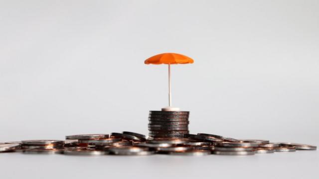 Um guarda-chuva laranja em uma pilha de moedas