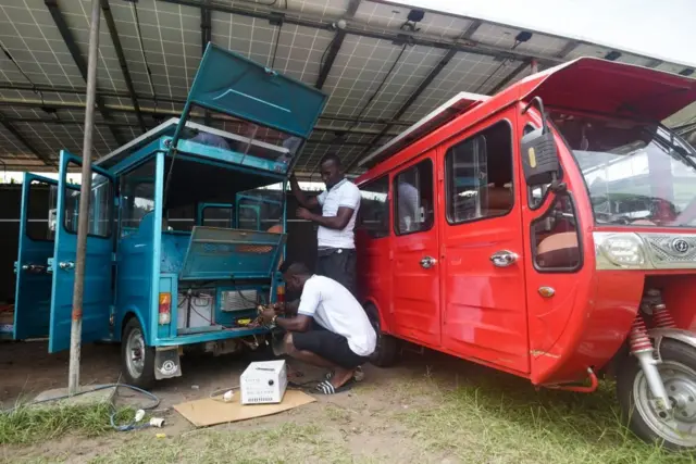 Des mécaniciens rechargent les batteries des taxis électriques à trois roues dans la ville côtière de Jacqueville. -Plusieurs véhicules électroniques chinois, équipés d'un système de rechargement d'énergie solaire, permettent au citoyen de Jacqueville de se déplacer facilement autour de la ville pour 100 à 500 francs CFA.