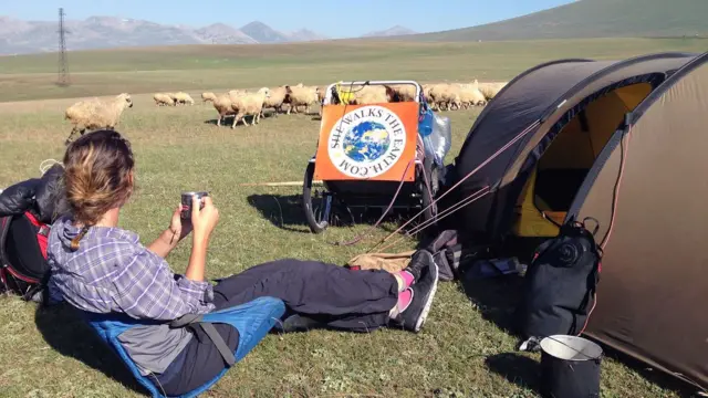 ผู้หญิงถือถ้วยนั่งข้างเต็นท์