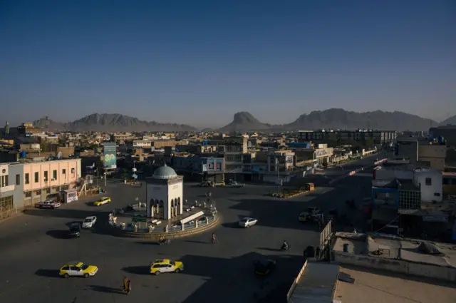 سه تاکسی زرد رنگ و دو ماشین دیگر دور چهارراهی شهیدان در مرکز شهر قندهار