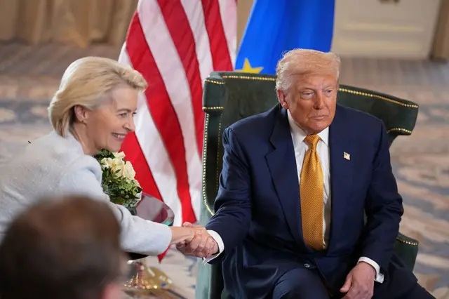 Von der Leyen ve Trump iki sandalyede oturmuş, el sıkışıyorlar.
