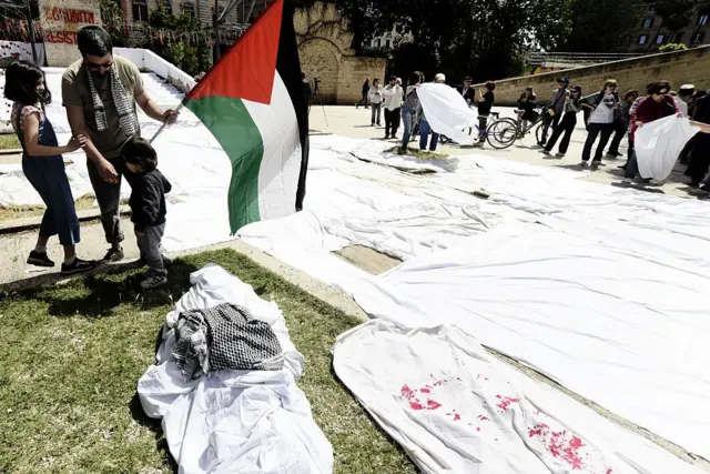 çarşaf geren bir adam elinde Filistin bayrağı tutuyor