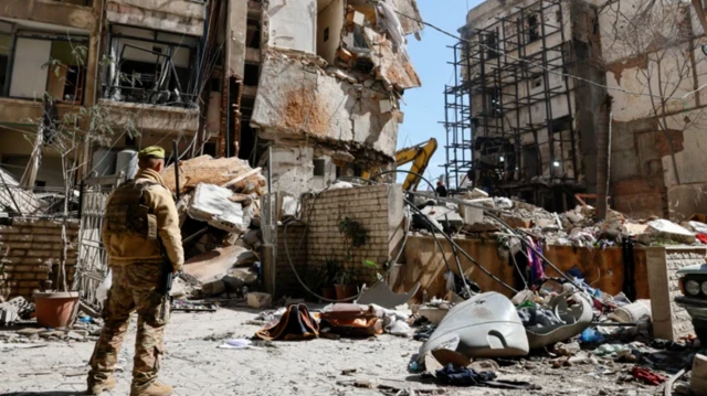 یک نیروی نظامی به ویرانه‌های ساختمان‌ها نگاه می‌کند