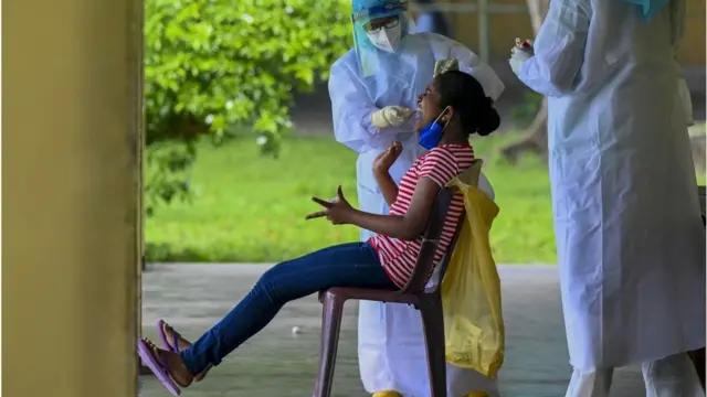 A resident reacts as a health worker collects a swab sample for the Covid-19 coronavirus