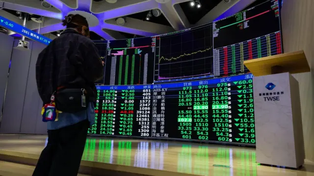 Человек смотрит на график тайваньского фондового рынка в офисе Тайваньской фондовой биржи в Тайбэе, Тайвань, 9 марта 2026 года.